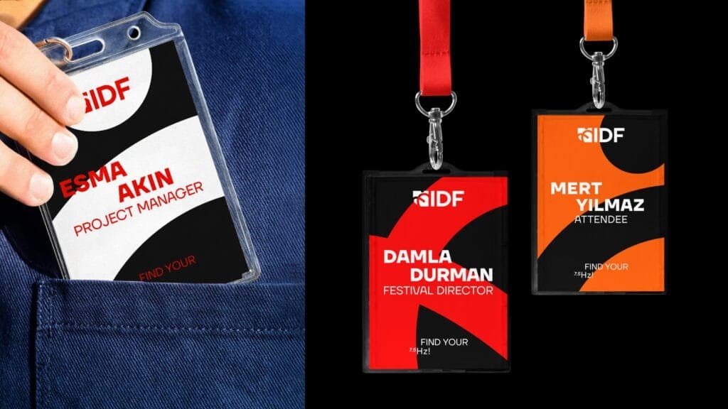 Close-up of event name badges for the Istanbul International Improvisation Dance Festival (IIDF). On the left, a badge for 'Esma Akın, Project Manager,' being placed into a pocket. On the right, two lanyard badges: one for 'Damla Durman, Festival Director,' in red and black, and another for 'Mert Yılmaz, Attendee,' in orange and black, featuring the festival’s 'Find Your 7.5 Hz!' slogan.