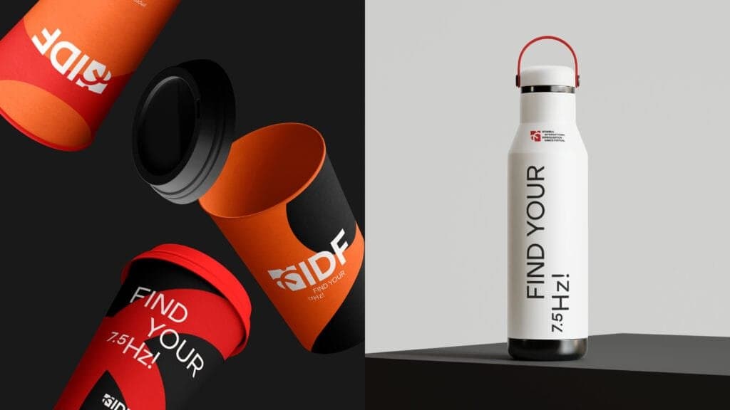 Stylish branded merchandise for the Istanbul International Improvisation Dance Festival (IIDF). On the left, vibrant red and orange reusable coffee cups featuring the IIDF logo and the slogan 'Find Your 7.5 Hz!' against a dark background. On the right, a sleek white reusable water bottle with the same slogan, paired with a red handle, showcasing eco-friendly and modern event branding.