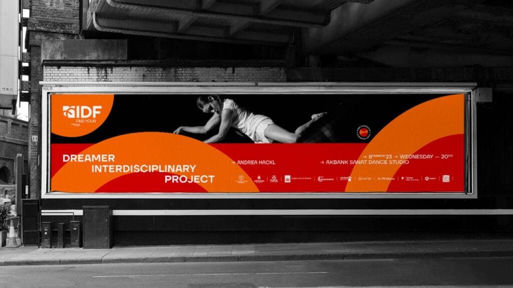 Large billboard advertisement for the IIDF (Istanbul International Improvisation Dance Festival) featuring the 'Dreamer Interdisciplinary Project' by Andrea Hackl. The bold orange and red wave design highlights event details, including the performance date, March 8, 2023, at Akbank Sanat Dance Studio, with a striking black-and-white image of a dancer in a dramatic pose as the centerpiece.